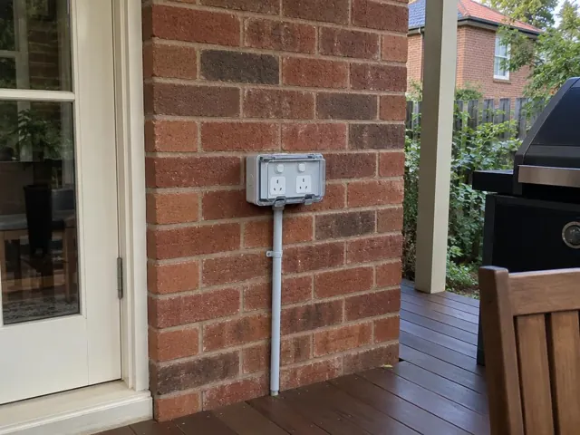 Outdoor double power point on a brick patio wall beside a glass door in Wollstonecraft